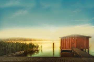 Fototapeta premium Fantastic Lichsstimmung on a lake with a boat and a boat shed. Concept: vacation and travel