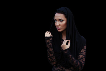 Young beautiful woman with a black hair in the black hood and blouse at the black background