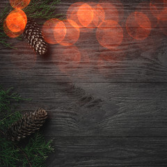 Christmas card. Black wood background, with branches and fir cones through the corners, top view....