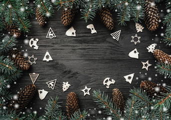 Xmas greeting card with snow effect. Text space, intro frame of fir branches and cones. Christmas wooden toys. Top view
