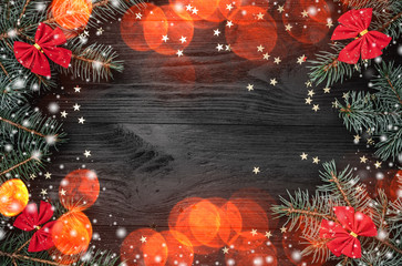 Xmas greeting card, on black wooden background. With fir branches and red bowls. Space for text....