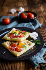 Puff pastry pies with egg, bacon, mushrooms and tomato