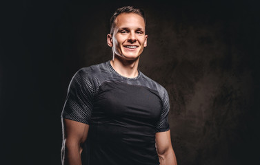 Portrait of a smiling sportsman looking at camera on dark background.