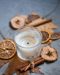 Close up of candle in colorful autumn leaves ana cinnamon