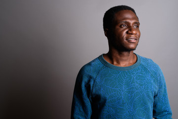 Fototapeta premium Young African man wearing blue long sleeved shirt against gray b
