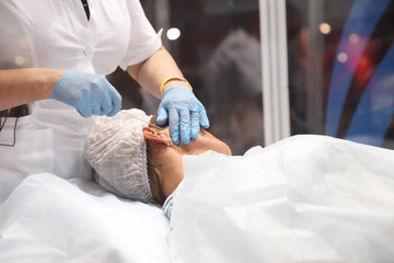 Surgeon operating on a woman when installing surgical threads for face lift