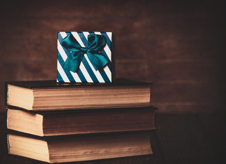 Books with gift box on wooden background. Photo in old color image style