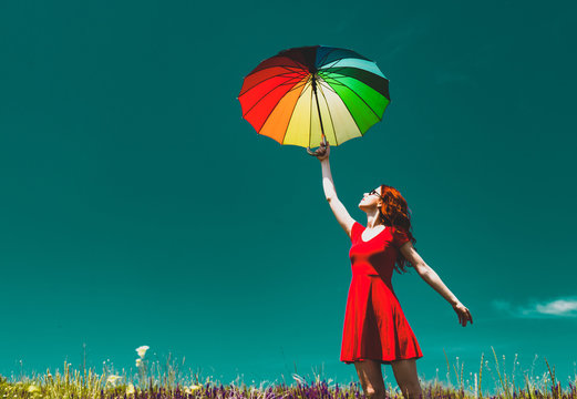 photo of the beautiful young woman with colorful umbrella in the field
