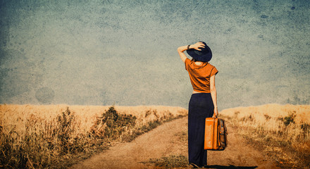 photo of the beautiful young woman with suitcase on the countryside road - obrazy, fototapety, plakaty
