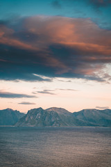 Sunrise and Sunset at Henningsvaer over atlantic ocean with pink clouds. The fishing village located on several small islands in the Lofoten archipelago, Norway over a blue sky with clouds.