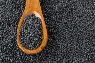 Heap of black organic beluga lentils in wooden spoon on black beluga lentils