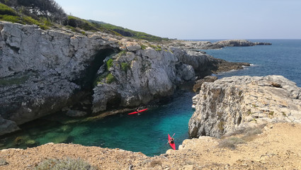 Fototapeta na wymiar davPuglia, Italy, August 2018, a small round bay in the Tremiti islands. Two canoeists on an excursion