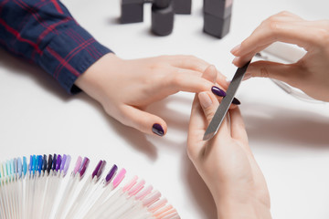 Hands of woman manicurist at work. Beautiful violet glossy nails - obrazy, fototapety, plakaty