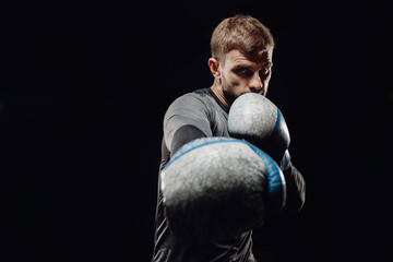 Male boxing in punching bag. Training man in gym.