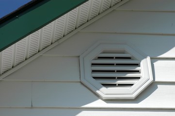 Obraz premium close up of white vinyl siding with air vent, soffit, and green fascia