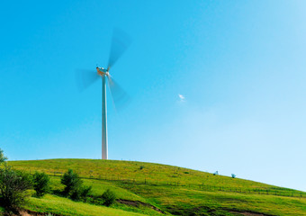 Fototapeta premium Windmill spinning on green valley