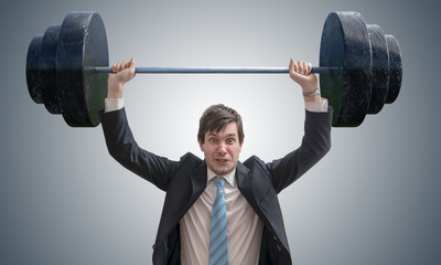 Young businessman in suit is lifting heavy weights.