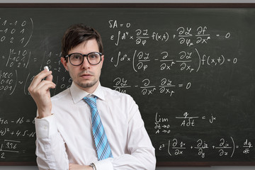 Young teacher in front of blackboard with math equations.