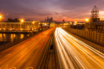 Road at night with the lights from many cars on the background of the metropolis.