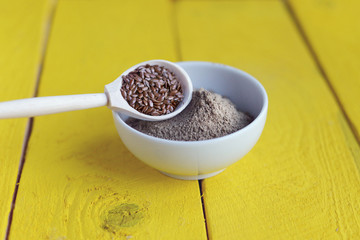 bowl of flax flour on a yellow wooden background