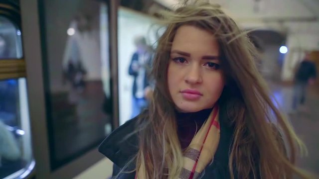 Girl With Swaying Hair By Wind From Underground Is Looking At Camera, Close-up Portrait