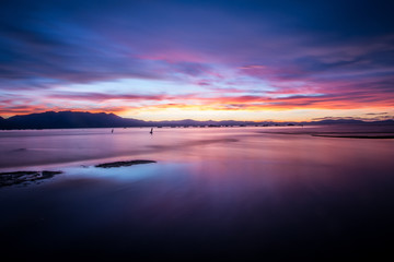 Fototapeta na wymiar Beautiful sunset on Lake Tahoe with bright purple, pinks and oranges in the sky. Long exposure, calm water