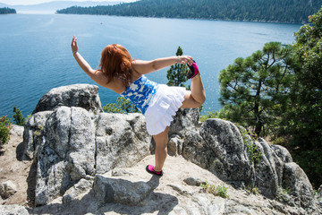 Red head hair ginger woman does a yoga mediation pose on a rock on Fannette Island in Lake Tahoe California