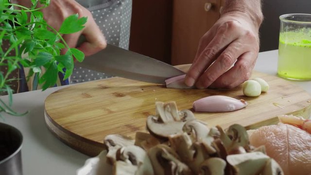 Chopping shallot on cutting board for preparing chicken marsala