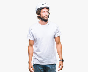 Handsome hispanic cyclist man wearing safety helmet over isolated background looking away to side with smile on face, natural expression. Laughing confident.