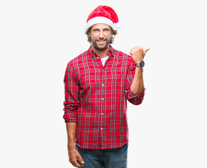 Handsome hispanic man model wearing santa claus christmas over isolated background smiling with happy face looking and pointing to the side with thumb up.