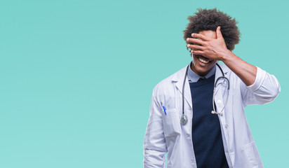 Afro american doctor man over isolated background smiling and laughing with hand on face covering eyes for surprise. Blind concept.
