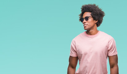 Afro american man wearing sunglasses over isolated background looking away to side with smile on face, natural expression. Laughing confident.