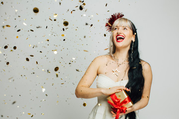 A wonderful time, fun portrait of a very happy young woman holding a present, surrounded by falling...