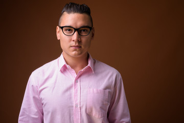 Young handsome multi-ethnic businessman against brown background