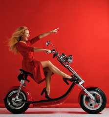Naklejka na ściany i meble Woman ride new electric car motorcycle bicycle scooter with hands pointing finger up freedom sign laughing smiling