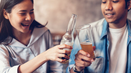 Friends are smiling, happy partying in the bar and talking and clinking bottles with beverages.