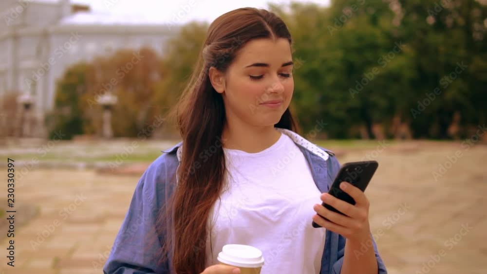 Poster caucasian woman messaging on mobile on the run drinking coffee to go using smartphone walking on the