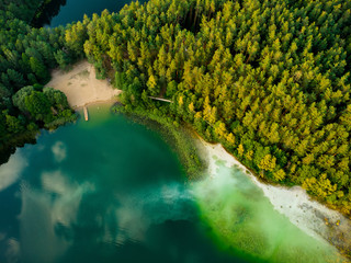 Aerial top down view of beautiful green waters of lake Gela. Birds eye view of scenic emerald lake surrounded by pine forests. - obrazy, fototapety, plakaty
