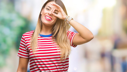 Young beautiful woman casual look over isolated background doing ok gesture with hand smiling, eye looking through fingers with happy face.