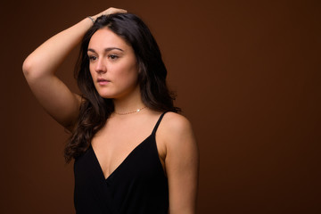 Naklejka premium Studio shot of young beautiful woman against brown background