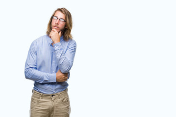 Young handsome man with long hair wearing glasses over isolated background with hand on chin thinking about question, pensive expression. Smiling with thoughtful face. Doubt concept.