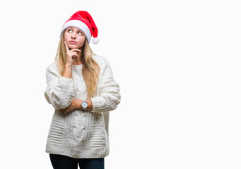 Young beautiful blonde woman wearing christmas hat over isolated background with hand on chin thinking about question, pensive expression. Smiling with thoughtful face. Doubt concept.