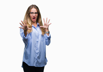 Young beautiful blonde business woman wearing glasses over isolated background afraid and terrified with fear expression stop gesture with hands, shouting in shock. Panic concept.
