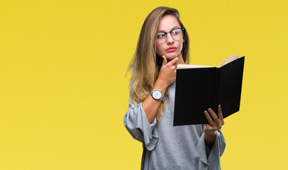 Young beautiful blonde woman reading a book over isolated background serious face thinking about question, very confused idea