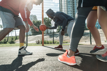 I have it. Free rules. Strong nice man taking a ball in his hands while playing street basketball with his friends © zinkevych