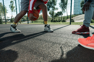 Sports games. Close up of an orange ball being in basketball players hands