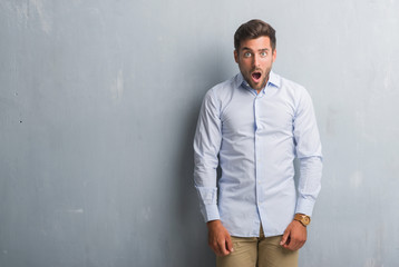 Obraz premium Handsome young business man over grey grunge wall wearing elegant shirt afraid and shocked with surprise expression, fear and excited face.