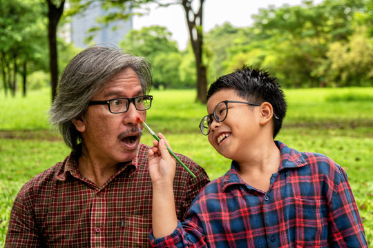 Asian father or grand father playing paint face together with son or grand son in the park