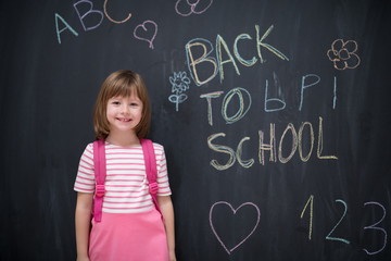 school girl child with backpack writing  chalkboard