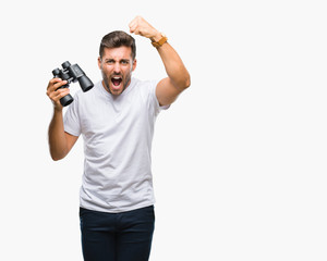 Obraz na płótnie Canvas Young handsome man looking through binoculars over isolated background annoyed and frustrated shouting with anger, crazy and yelling with raised hand, anger concept